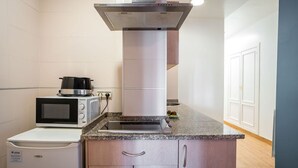 A compact kitchen with a microwave, a small refrigerator, and a stove. - QH Granada Center 13 (Granada)