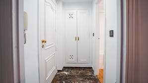Ein Flur mit weißen Türen, Marmorboden und einer Leuchte an der Decke.