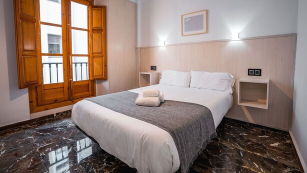 Ein Hotelzimmer mit Bett, Holzschrank, Marmorboden und einem Balkon mit Holzhörnern.