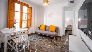 Ein modernes Wohnzimmer mit einer Couch, einem Esstisch mit Stühlen und einer Deckenleuchte.