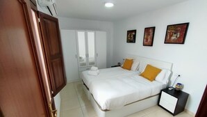 Een slaapkamer met een bed, nachtkastje, kast en een deur.