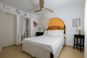 Une chambre à coucher comprenant un lit, un ventilateur de plafond, une table de chevet et une commode.
