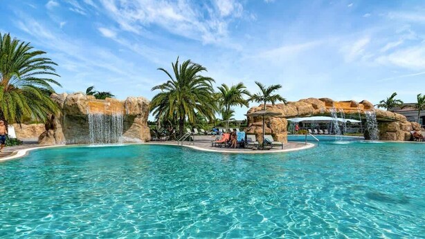 A clear blue pool with waterfalls and palm trees. - Golf Course Townhome Resort Amenities 2B Luxury (Bradenton)