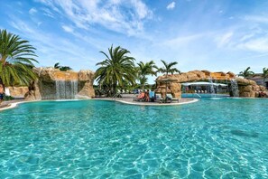 A clear blue pool with waterfalls and palm trees. - Golf Course Townhome Resort Amenities 2B Luxury (Bradenton)