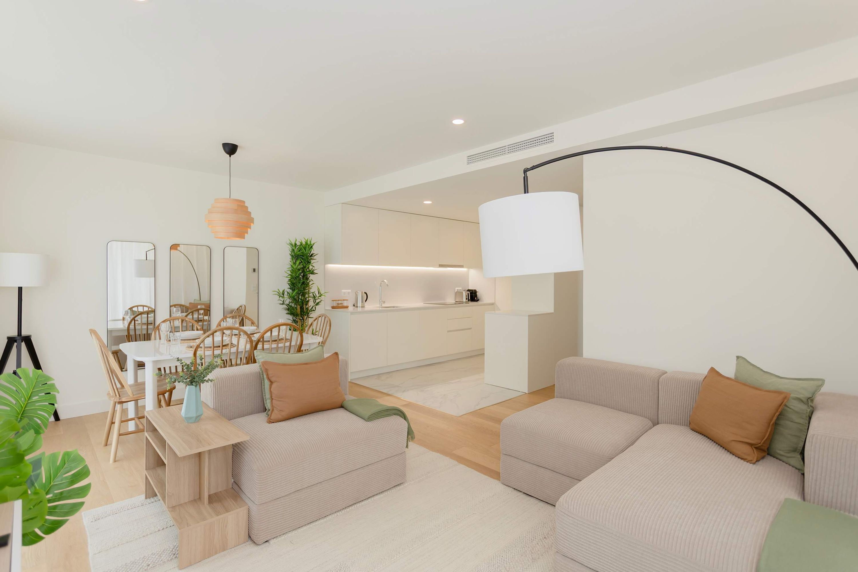 A modern living room with a sofa set, a dining table with chairs, and a kitchen area in the background.