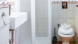 Et badeværelse med brusebad, toilet og håndvask.