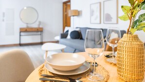 Et spisebord dækket med tallerkener, bestik og glas, med en fletkurv og en plante på bordet.