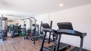 A gym with treadmills, weight machines, and a mirror wall. - Condominium on the Coast in Imbassai - SOV (Mata de São João)