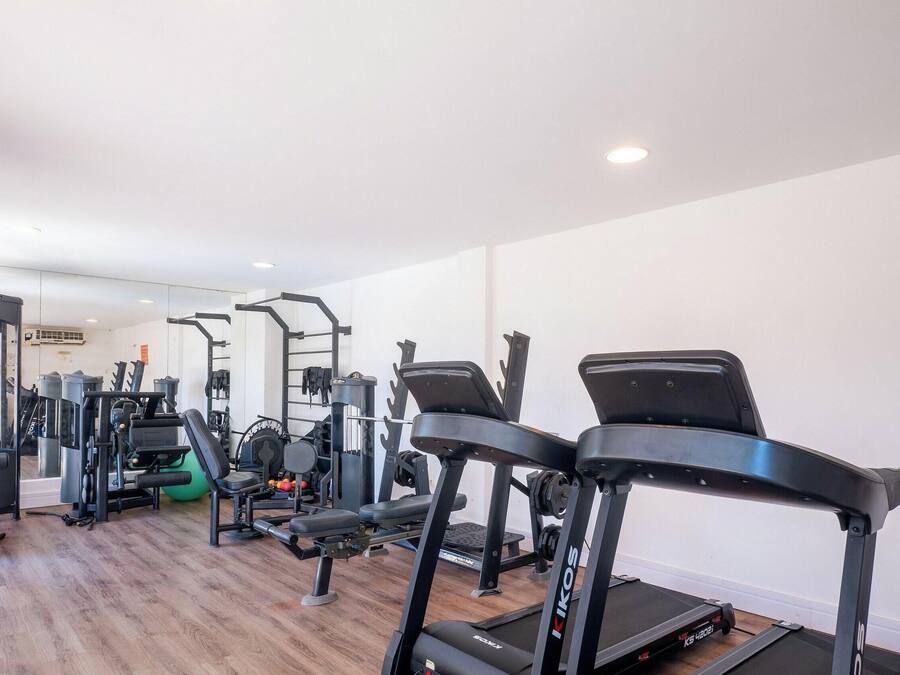 Ein Fitnessstudio mit Laufbändern, Krafttrainingsgeräten und einer Spiegelwand.