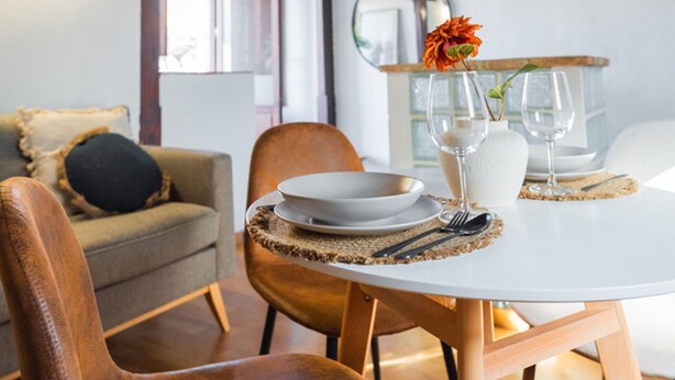 A dining area with a round table, chairs, and a vase with flowers. - Quality Homes Granada - QH Correo Viejo 08 (Granada)