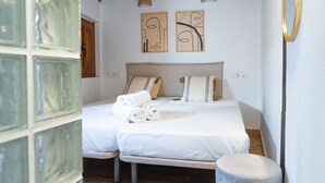 A bedroom with a bed, two wall-mounted light fixtures, and two abstract wall art pieces. - Quality Homes Granada - QH Correo Viejo 08 (Granada)