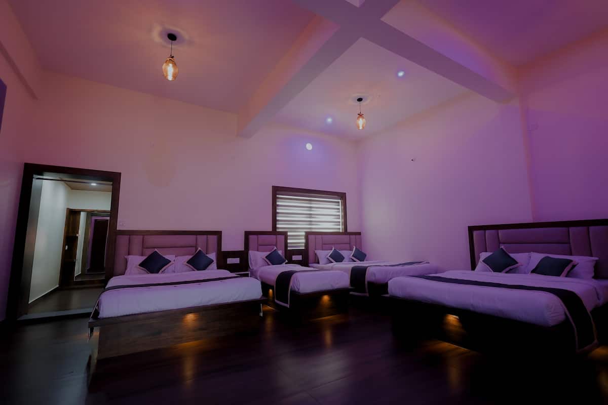 Une chambre d’hôtel avec trois lits, un plancher en bois et un grand miroir.