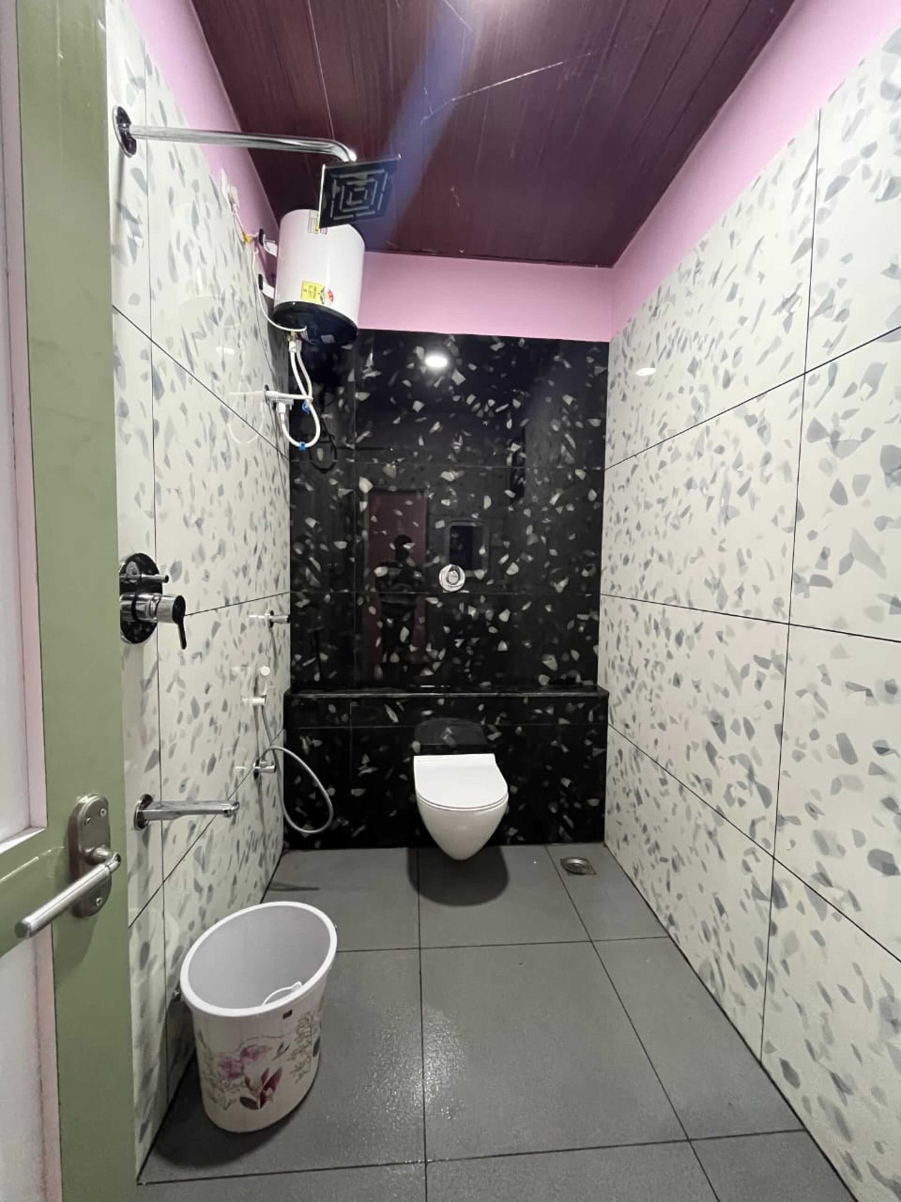Ein kleines Badezimmer mit Toilette, Dusche und Eimer.