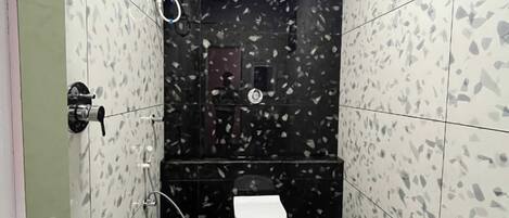 Ein kleines Badezimmer mit Toilette, Dusche und Eimer.