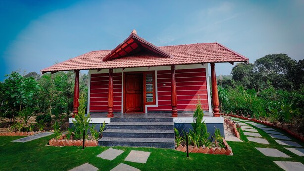 A red building with a tiled roof, a wooden door, and a small porch with steps leading to the entrance. - Mountain Peak Resort  (Alur)