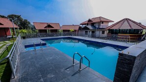 A swimming pool with a tiled deck, metal railings, and a clear blue water surface. - Mountain Peak Resort  (Alur)