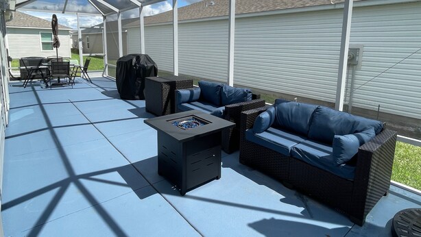 Een overdekte patio met buitenmeubels, waaronder een bank, stoelen en een salontafel.