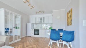 A modern kitchen with white cabinets, a built-in oven, and a dining area with blue chairs.