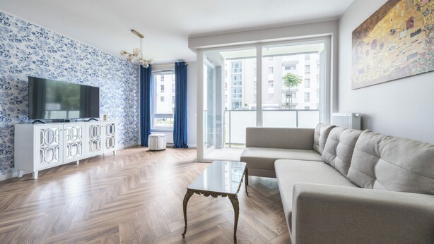 A modern living room with a sofa, TV, and wooden flooring.