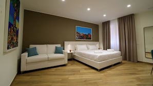 A hotel room with a bed, a sofa, a nightstand, and a painting on the wall. - Maqueda Room & Suite (Palermo)