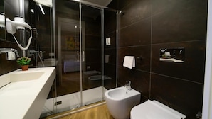 A modern bathroom with a glass shower enclosure, a pedestal sink, and a bidet. - Maqueda Room & Suite (Palermo)