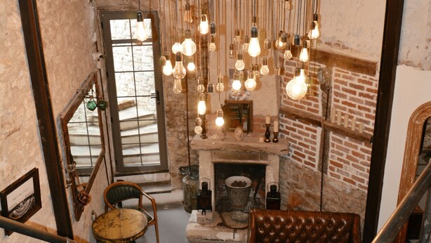 A loft-style room with exposed brick walls, a fireplace, and a hanging light fixture. - 8 Design Urla (Urla)