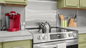 A modern kitchen with stainless steel appliances, including a coffee maker, kettle, and stove.