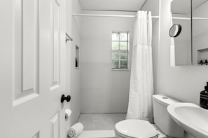 A bathroom with a toilet, sink, and a window.