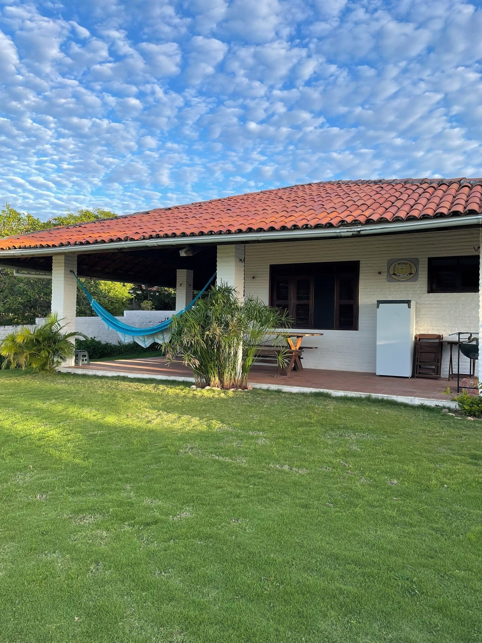 Ein Haus mit rotem Ziegeldach, einer Veranda und einem kleinen Garten.