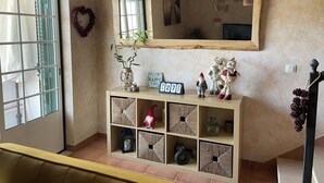 A room with a wooden console table, a mirror, and shelves with decorative items. - Refúgio da Longueira (Longueira)