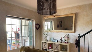 A living room with a sofa, a large window, a mirror, and a staircase. - Refúgio da Longueira (Longueira)
