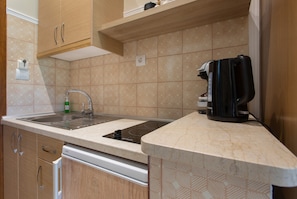 A kitchen with a sink, stove, and a coffee maker. - Deluxe Apartment with Balcony and Sea View 2 with Private Terrace, Wi-Fi and Air Conditioning (Vasilikos)