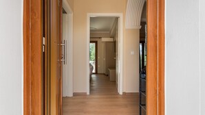 Een gang met houten vloer, witte wanden en een deur naar een andere kamer.