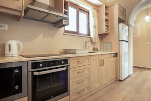 A modern kitchen with built-in appliances, wooden cabinets, and a window with curtains.