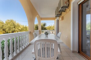 Ein Balkon mit Tisch und Stühlen, einem Blumentopf und Blick auf Bäume.