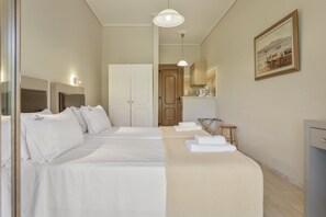 Hotellihuone, jossa on kaksi sänkyä, puuovi, taulu ja pieni jakkara.