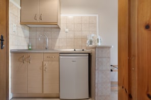 A compact kitchen with wooden cabinets, a dishwasher, a sink, and a coffee maker. - Studio Apartment 'Standard  with Sea View 2' with Shared Terrace, Wi-Fi and Air Conditioning (Vasilikos)