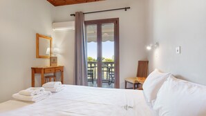 A hotel room with a bed, a desk with a lamp, a chair, and a balcony with a view.