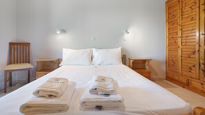 A hotel room with a large bed, two bedside tables, a wooden wardrobe, and a chair.