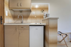 Una cocina compacta equipada con lavavajillas, armarios de madera, un lavamanos y una cafetera.