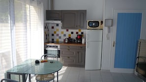 Een kleine keuken met een magnetron, koffiezetapparaat en een koelkast.