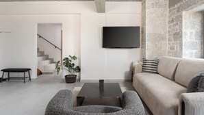 Uma sala de estar moderna com televisão de tela plana na parede, um sofá, uma mesa de centro e uma escada que leva a outro andar.