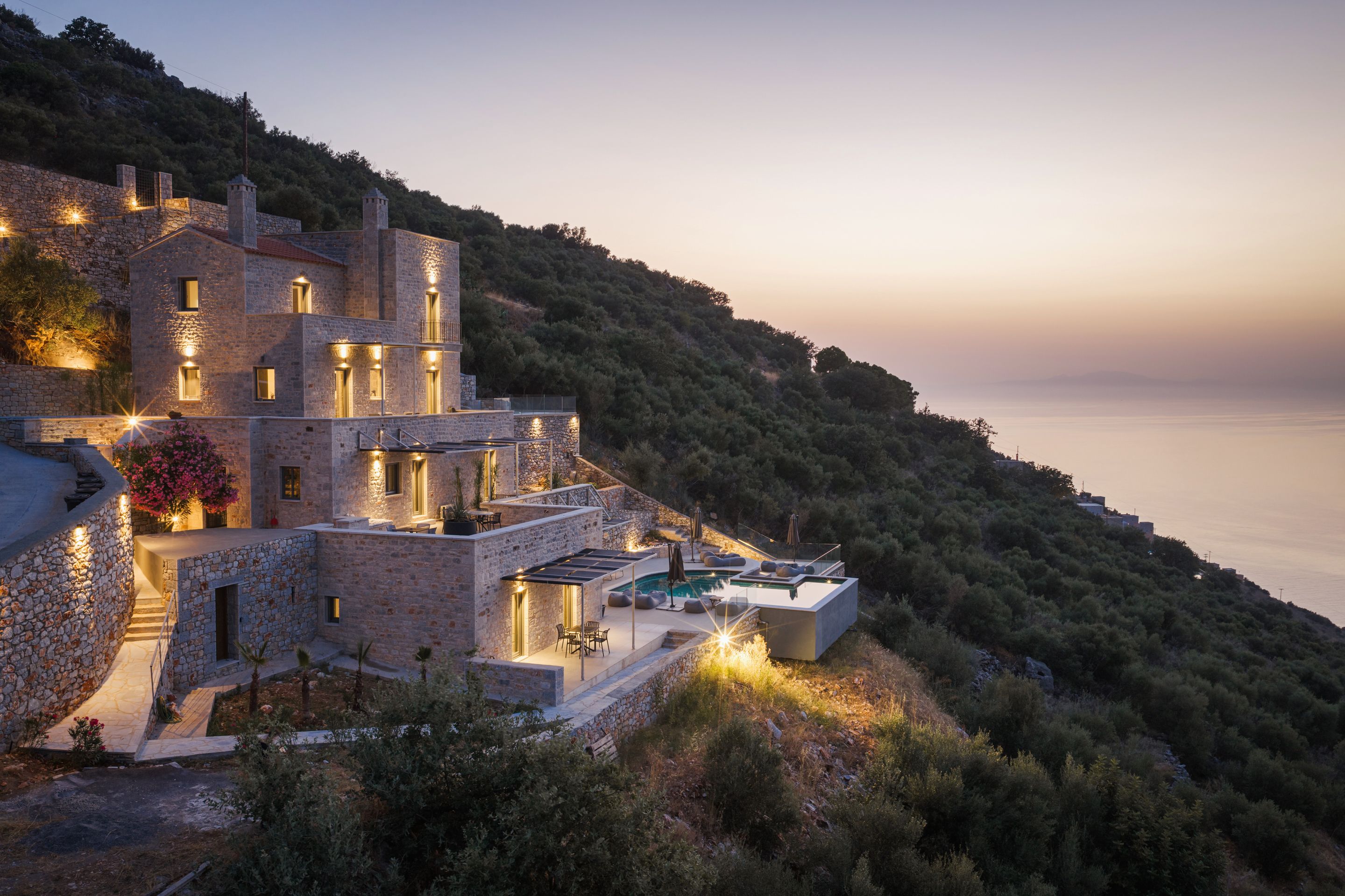 A stone villa with multiple levels, a swimming pool, and a view of the sea.