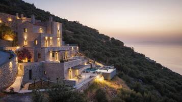 A stone villa with multiple levels, a swimming pool, and a view of the sea.