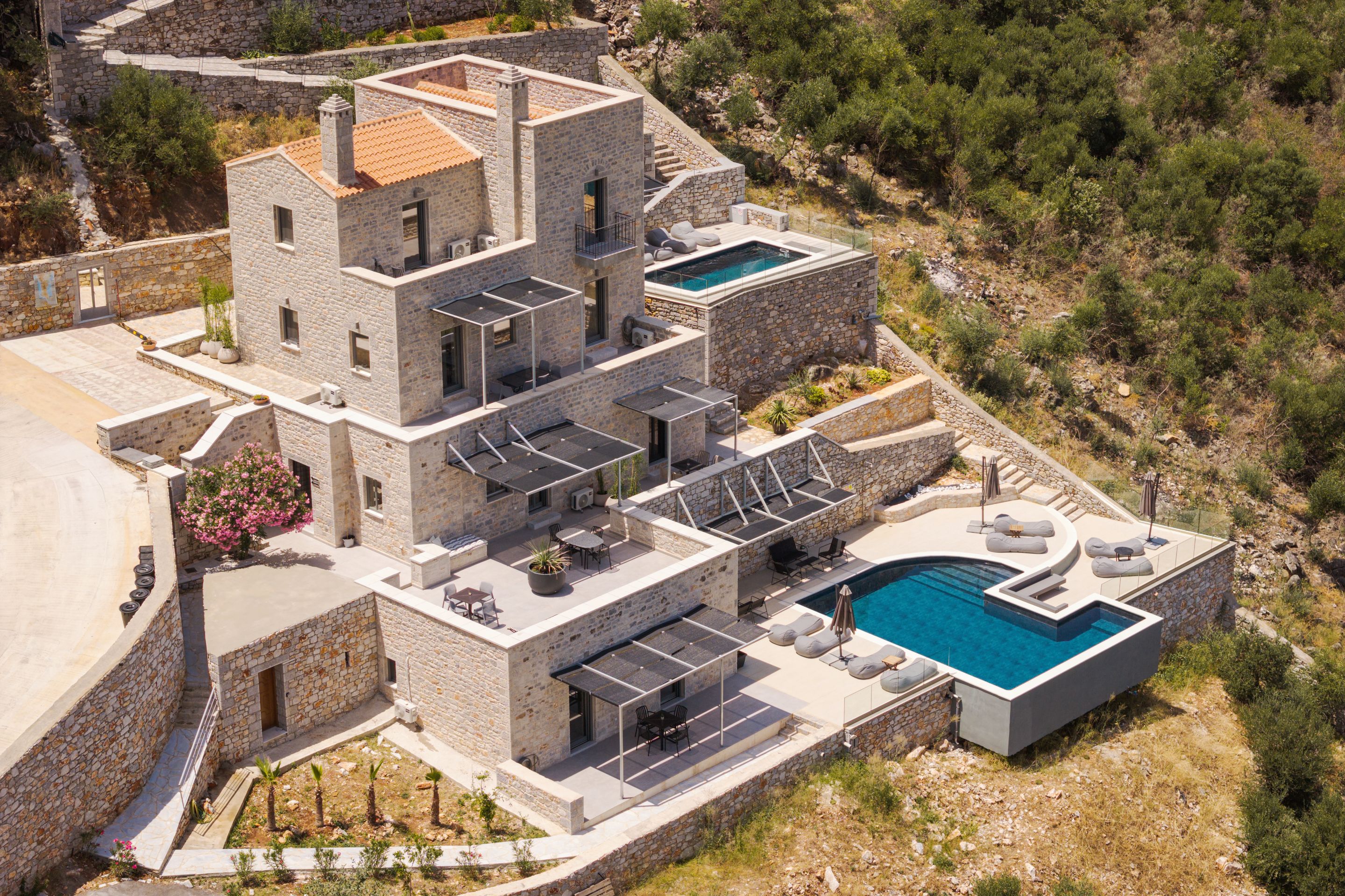 A multi-story stone building with a rooftop pool and outdoor seating areas.