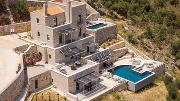 A multi-story stone building with a rooftop pool and outdoor seating areas.