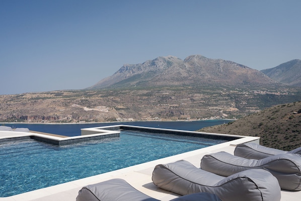 An infinity pool with a view of mountains and a body of water.
