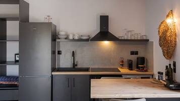 Eine moderne Küche mit Einbaukühlschrank, Herd und Spüle. Ein Holztisch mit Stühlen steht daneben.
