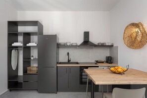 A modern kitchen with a built-in refrigerator, a sink, and a wooden dining table with a fruit bowl.