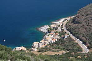 A coastal village with buildings along a narrow road, overlooking the sea.